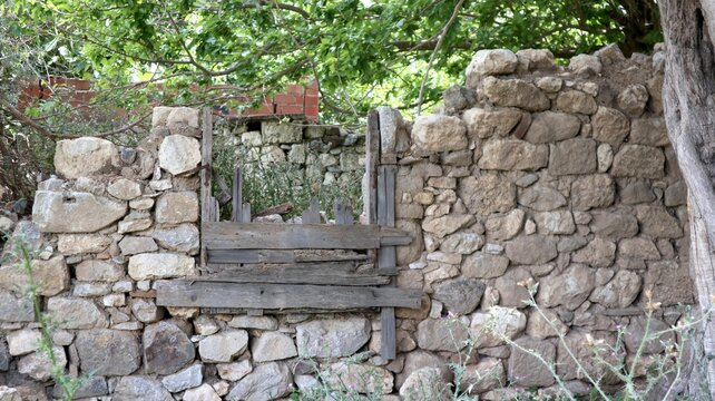 A dilapidated stone wall with a wooden window frame still visible.
