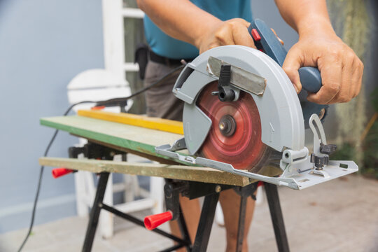 Circular saw straight rip cut MDF wood plank on sawhorses.