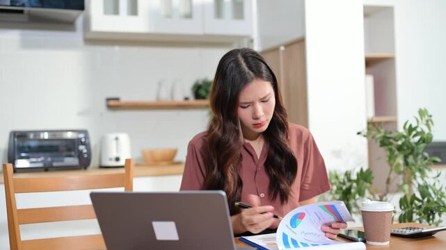Two beautiful young Asian women smiling while blending a healthy green vegetable smoothie and preparing fresh food in kitchen.