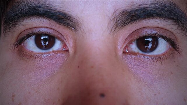 Close up on the eye of an adult asian man looking at the camera with a calm and focused expression, conceptualizing vision, health, awareness, and modern human lifestyle.