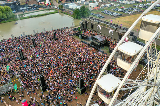 Herzogenaurach, Germany - 24 July 2025: Aerial view of the Open Beatz Festival with a large crowd gathered in front of the main stage, a ferris wheel, and a small pond.