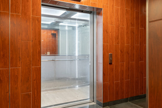 Glass elevator in a modern building with wood paneling