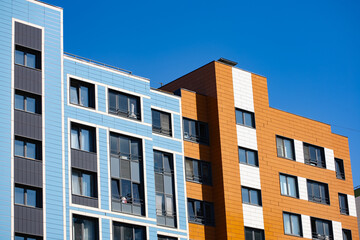 Obraz premium Modern colorful apartment building with blue and orange facade against clear sky