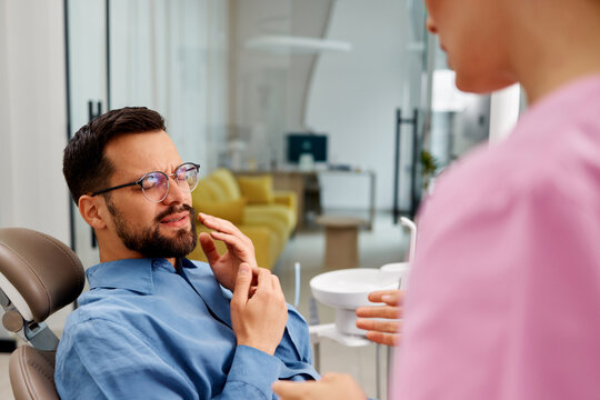 Patient suffering toothache talking to dentist in clinic