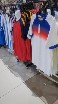 A row of colorful soccer jerseys hanging on a display rack inside a clothing store, featuring various national team and club inspired sports apparel designs.