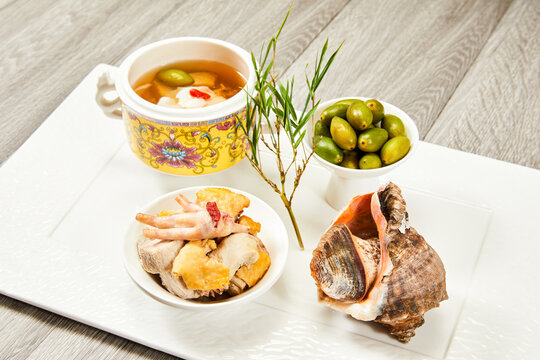 Gourmet conch seafood dish with green olives and broth
