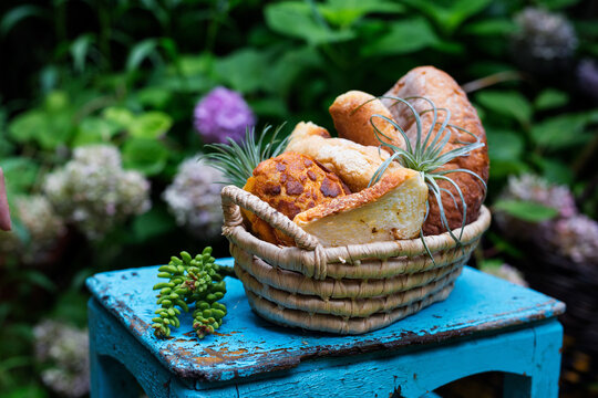 Basket of assorted bread on rustic blue stool in garden