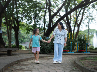 Obraz premium Happy Asian mother holding hands with her young daughter walking together after school.