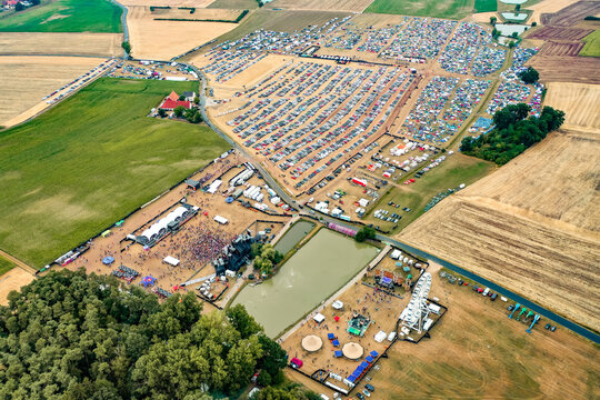 Herzogenaurach, Germany - 22 July 2022: Aerial view of Open Beatz Festival featuring multiple stages, large crowds of people, and vast camping and parking areas set amidst rural fields.