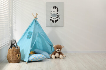 Wigwam, toys and pillows near white wall in child's room, space for text © New Africa