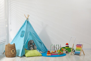 Wigwam, toys and pillows near white wall in child's room © New Africa