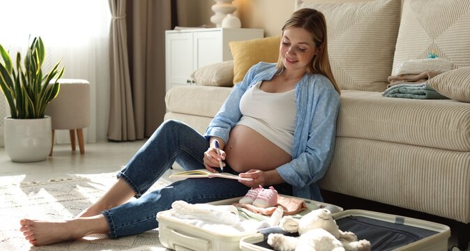 Pregnant woman writing packing list for maternity hospital at home