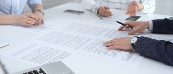 Business partners discussing contract terms, reviewing legal documents during an office meeting,...
