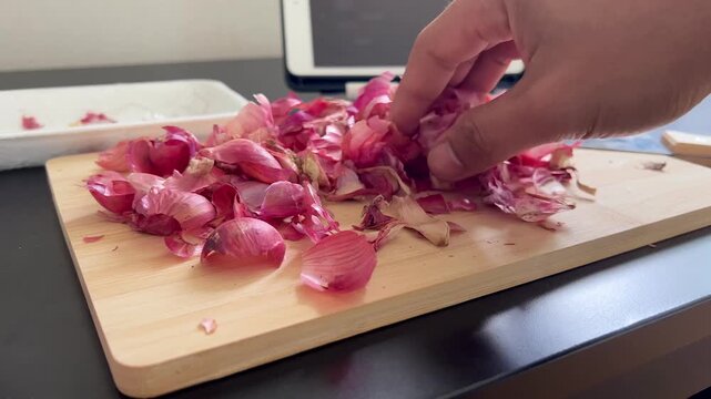Close up Hand takes shallots peel on a wooden board 