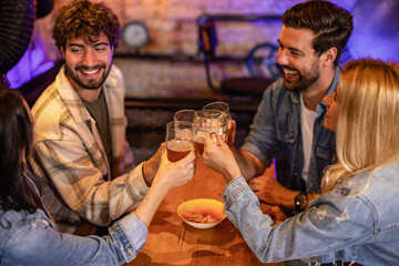 Friends toasting with beer glasses in modern pub
