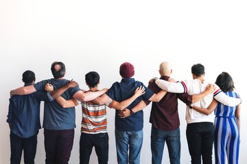 Naklejka premium Group of diverse people standing together, arms linked. Unity and diversity. Back view of individuals in casual attire, showing solidarity and connection. Diverse group of people.