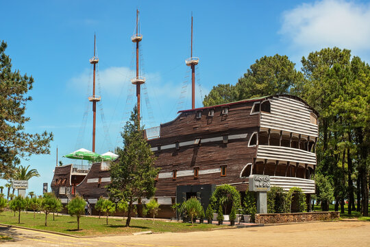 Batumi, Georgia - May 23, 2026: A unique restaurant housed in a large wooden ship structure named "New Ship," located in a green park area near the seaside in Batumi on a sunny day.