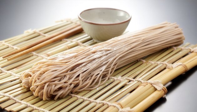 Raw buckwheat soba noodles bamboo mat wooden chopsticks empty ceramic dipping bowl. Ideal for asian cuisine restaurant menus or recipe blogs. Highquality photo for food packaging or cooking instructio