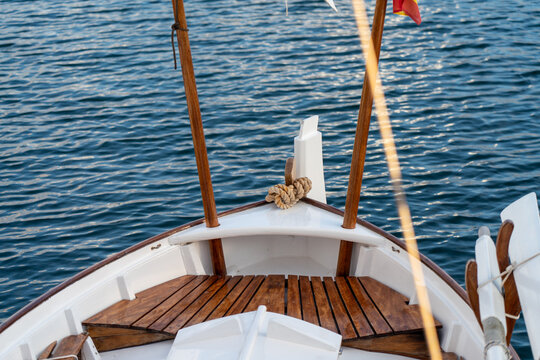 Close-up of a traditional wooden llaut boat bow on the turquoise Mediterranean sea water. Nautical details, luxury yachting, slow living and summer vacation concept.