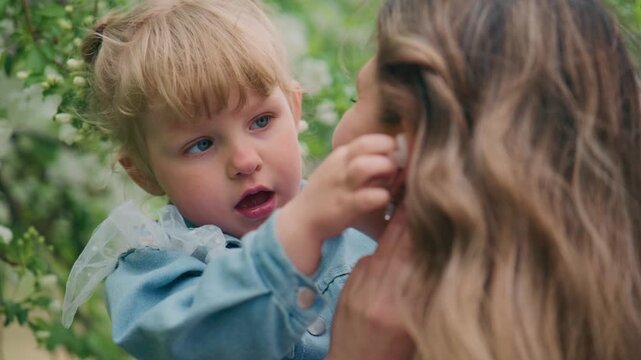 Young child giggles while being held by a smiling adult. Soft greenery frames the tender moment. Natural light highlights joyful interaction. Perfect for family, parenting, or childhood themes