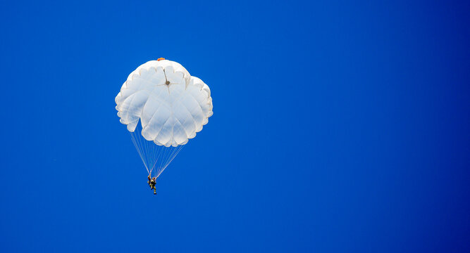 Skydiving. Flying parachutists against the background of the blue sky and mountains. Extreme sport and entertainment.