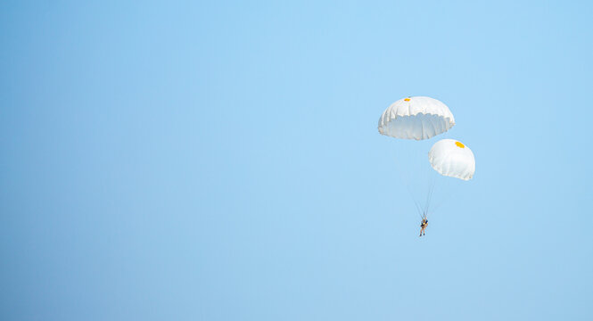 Skydiving. Flying parachutists against the background of the blue sky and mountains. Extreme sport and entertainment.