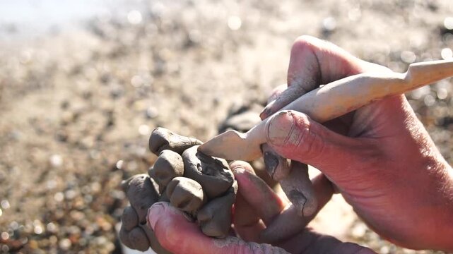 Clay hands craft, sculpting small object on sunny beach by water, artistic creation outdoors