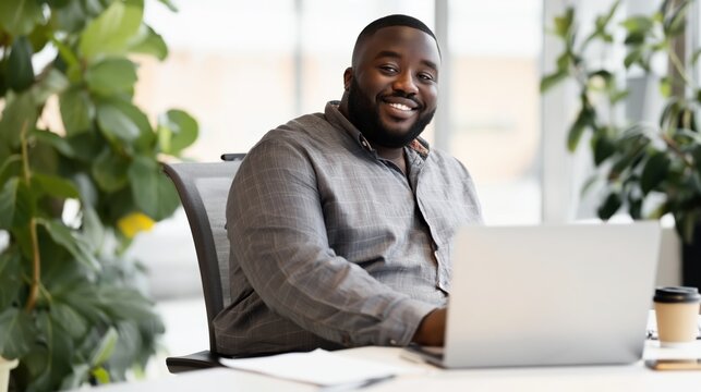 Smiling businessman working on laptop in modern office