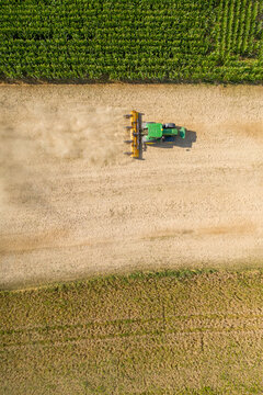 Nuremberg, Germany - 02 May 2026: Aerial view of a tractor tilling the soil in Knoblauchsland, kicking up dust between lush green crop fields under bright sunlight.