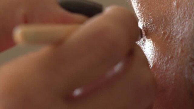 Eye makeup application, beauty professional applying cosmetics to lower eyelid with brush, extreme close-up shot