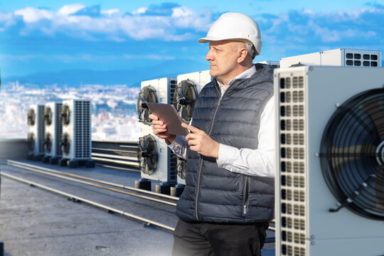 HVAC engineer inspects rooftop air conditioners, climate system maintenance and building service