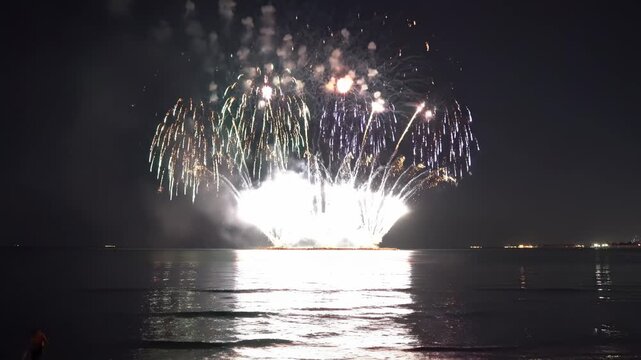 Colorful fireworks exploding over ocean water at night