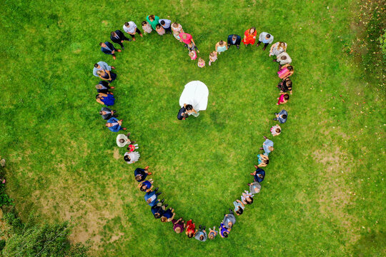 Wiesenthau, Germany - 02 May 2026: Aerial view of wedding guests forming a heart shape around a bride and groom on the green lawn of Schloss Wiesenthau.