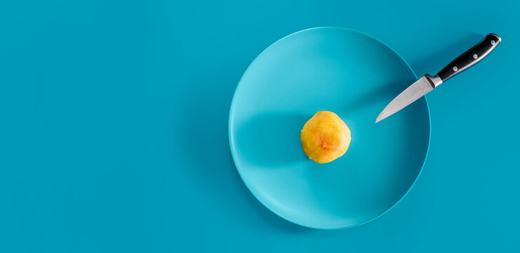 Very small portion of food on a blue plate with a knife, top view, minimalist composition symbolizing dieting, calorie restriction, hunger, scarcity and weight loss control