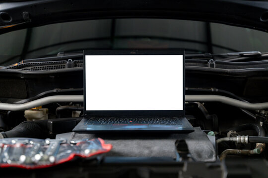 A laptop computer sits on a vehicle's engine block during a computer-aided diagnostic check.