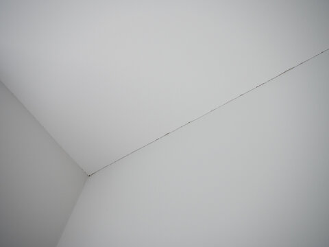 White room ceiling with drywall taped to wall joint and visible gap between plaster and gypsum board after interior renovation work.