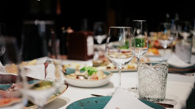 Empty glasses and various appetizers arranged on a beautifully set table in restaurant preparation for an event.