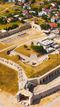 Vertical video. Seddulbahir, Eceabat, Turkey. Sedd el Bahr Fortress, angular stone bastions and earthen ramparts, aerial view over turquoise Dardanelles waters on a clear summer day. Aerial View, Dep