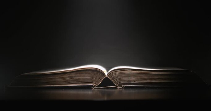 Old Book Illuminated. Timeworn Book Laid Open In Warm Ambient Light With Dust Motes Floating Around