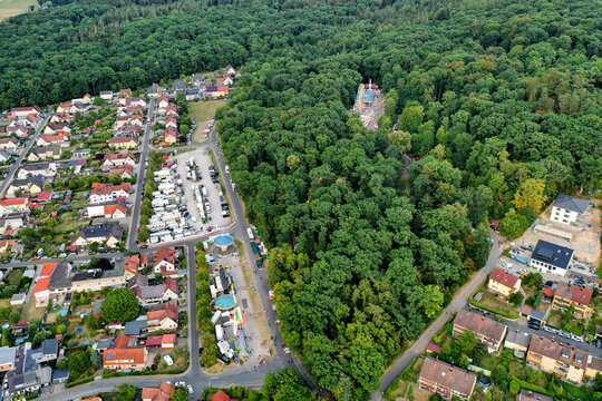 Forchheim, Germany - 26 July 2025: Aerial view of Annafest festival grounds with stalls and rides nestled between residential houses and a dense green forest.