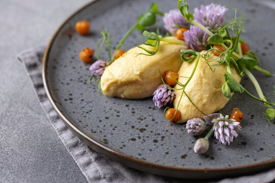 Healthy Homemade Creamy Hummus with pea sprouts and chives flowers. Quenelle from dip.