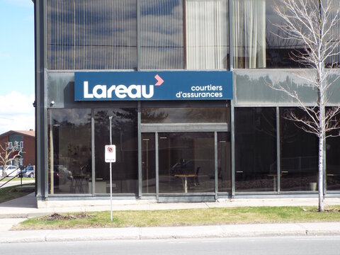 Gatineau, Quebec, Canada &ndash; April 21, 2026: An office storefront displays a blue sign for "Lareau courtiers d'assurances" above large glass windows along a city sidewalk at 770 Boulevard Saint-Joseph.
