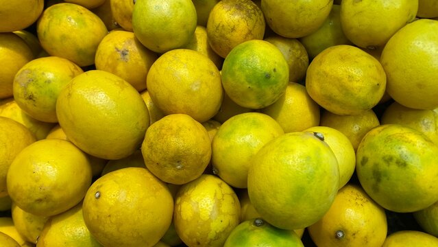 A vibrant close-up of fresh yellow and green citrus fruits, piled high, ready to deliver zesty flavor to healthy dishes and refreshing beverages