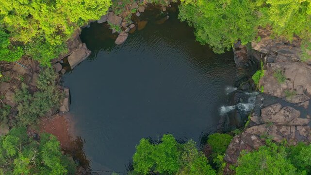 Aerial top down view of beautiful tropical waterfall and natural rock pool in green jungle 4K