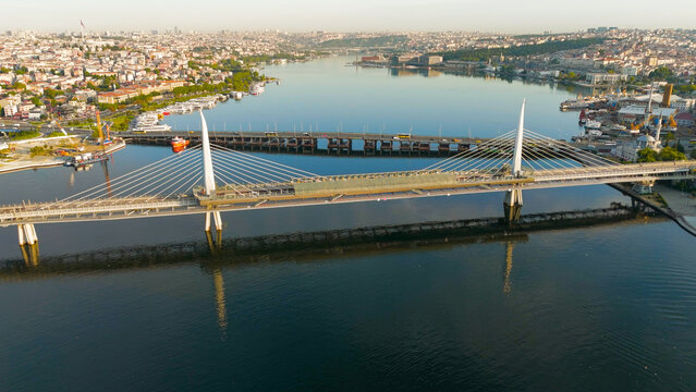Istanbul, Turkey. Golden Horn Bridge and Halic Metro Station with pedestrian bridge across the Golden Horn illuminated by the morning sun. Aerial View