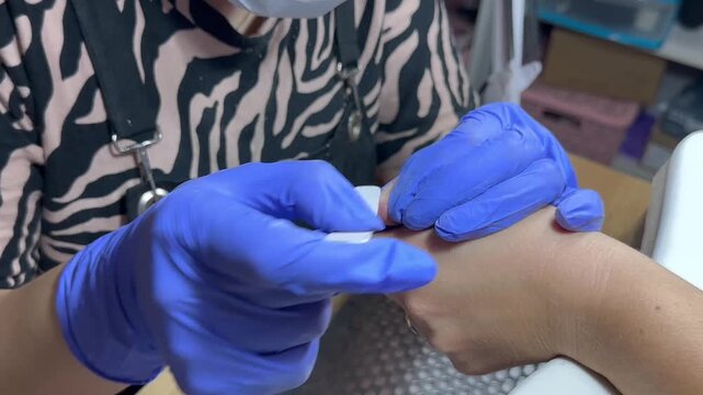 Video of a nail technician filing nails. Manicurist shapes nail using salon nail file during cosmetic procedure in beauty salon. Woman gets a french manicure at a beauty salon, manicurist files her cu