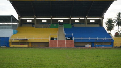 Empty sports stadium stands with yellow and blue seats © Iin Aprilia