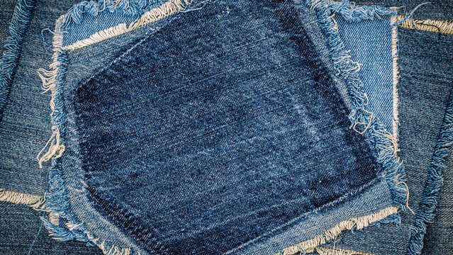 Denim fabric pieces arranged in a pattern on a flat surface with frayed edges used for clothing design at a workshop