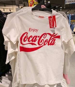 Camiseta de manga corta con etiqueta y el lema Enjoy Coca-Cola con la tipograf&iacute;a cl&aacute;sica de la compa&ntilde;&iacute;a, en tienda Primark de Madrid, Espa&ntilde;a, 7 de abril de 2026