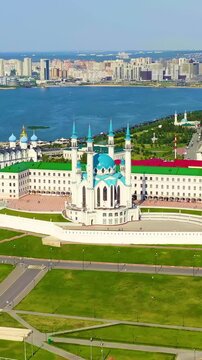 Vertical video. Kazan, Russia. The Kazan Kremlin, its white limestone walls and towers enclosing the Kul Sharif Mosque with blue domes and minarets, aerial panoramic view over the Kazanka River under
